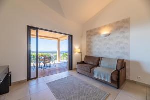 a living room with a couch and a balcony at Résidence Les Terrasses de Rondinara in Bonifacio