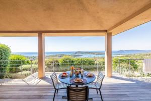 a table and chairs on a deck with a view at Résidence Les Terrasses de Rondinara in Bonifacio