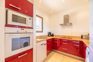 a kitchen with red cabinets and a microwave at Résidence Les Terrasses de Rondinara in Bonifacio