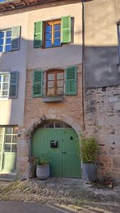 a building with a green door and some windows at Maison atypique médiévale in Saint-Léonard-de-Noblat