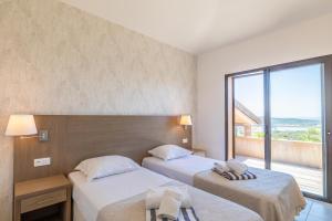 two beds in a room with a large window at Résidence Les Terrasses de Rondinara in Bonifacio