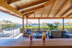 a patio with tables and chairs and a view of the beach at Résidence Les Terrasses de Rondinara in Bonifacio