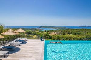 a person laying in a swimming pool at a resort at Résidence Les Terrasses de Rondinara in Bonifacio