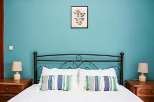 a bedroom with blue walls and a bed with two lamps at Villa Sunrise apartment in Gouvia