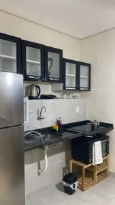 a kitchen with black cabinets and a stainless steel refrigerator at Top Coliving II in Cuiabá