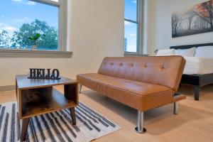 a living room with a brown leather couch and a bed at Bright and Modern Studio in Louisville # 302 in Louisville