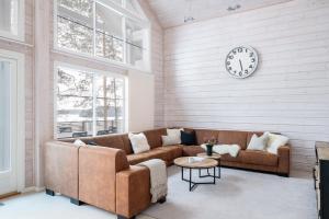 a living room with a couch and a clock on the wall at Villa Lago - High Quality Villa for up to 20 guests in Tahkovuori