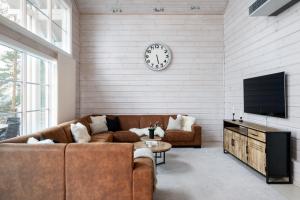 a living room with a couch and a clock on a wall at Villa Lago - High Quality Villa for up to 20 guests in Tahkovuori +45 photos