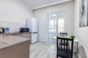 a kitchen with a white refrigerator and a table at RAISSON APARTHOTEL AM85 Хан Шатыр in Taldykolʼ