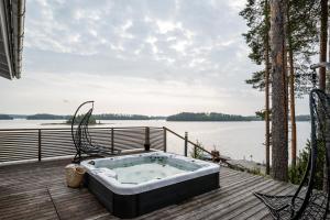 a bath tub sitting on a deck next to a body of water at Villa Lago - High Quality Villa for up to 20 guests in Tahkovuori