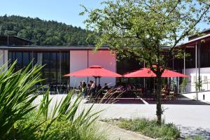 un ristorante con ombrelloni rossi di fronte a un edificio di Bildungshaus Arbogast a Götzis