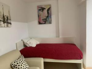 a bedroom with a red bed and a couch at Charming T1 apartment in Seixal in Aldeia de Paio Pires +29 photos