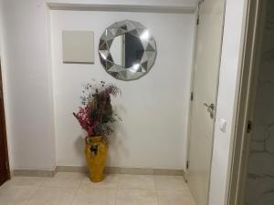 a hallway with a mirror and a vase with flowers at Charming T1 apartment in Seixal in Aldeia de Paio Pires
