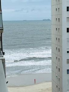 a person standing on the beach near the ocean at Vista ao Mar Praia Pitangueiras Servico de praia Garagem in Guarujá
