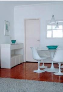 a white kitchen with a table and two white chairs at Vista ao Mar Praia Pitangueiras Servico de praia Garagem in Guarujá +19 photos