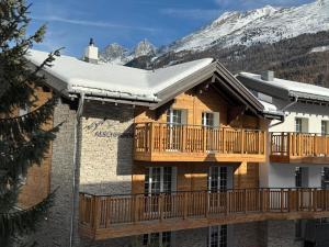 a log home with a deck and snowy mountains at Chalet Aeschhorn in Zermatt
