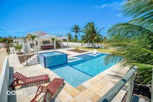 una piscina con dos sillas y una casa en Qavi - Casa Palm Paradise #ParaisoDoBrasil, en Touros