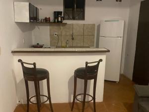 a kitchen with two bar stools and a white refrigerator at Casa por do sol Angra in Angra dos Reis