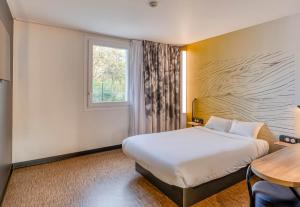 ein Hotelzimmer mit einem Bett und einem Fenster in der Unterkunft B&B HOTEL Bordeaux Saint André de Cubzac in Saint-André-de-Cubzac + 39 Fotos