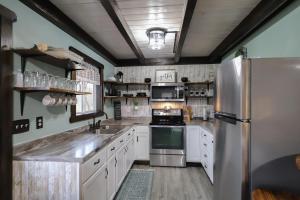 una cucina con mobili bianchi e un frigorifero in acciaio inossidabile di Eagle Lake Cottage a Dunnville