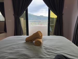 a towel laying on a bed in front of a window at Condo Istana Penthouse in langkawi in Kuah