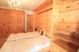 a bedroom with a bed with wooden walls and a chandelier at Apartment Christina in Pontresina
