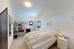 una camera da letto bianca con un grande letto con lenzuola bianche di Apartment Gianda Verda C31 a Surlej