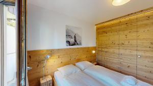 ein Bett in einem Zimmer mit einer Holzwand in der Unterkunft Apartment Sungold in St. Moritz