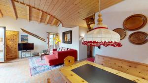Una sala de estar con una mesa y un sofá rojo. en Apartment La Dmura, en Samedan