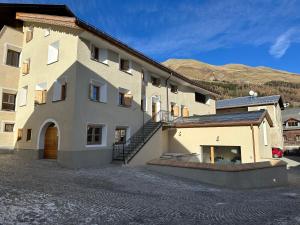 a large white building with a staircase next to it at Chesa Unica - Giardin in Zuoz