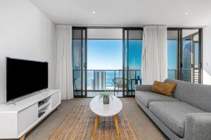 黄金海岸Modern 2BR Broadbeach Ocean Hinterland Views的客厅里有一张沙发和一台电视