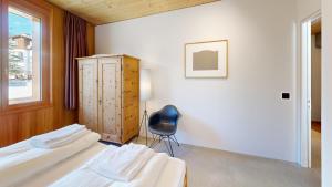 ein Schlafzimmer mit 2 Betten und einem Stuhl darin in der Unterkunft Apartment Sella Nouva in Pontresina