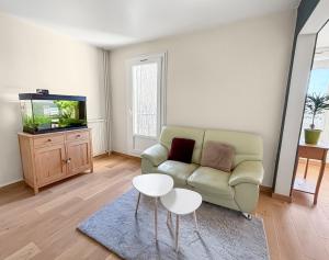 a living room with a couch and a tv at Spacieux, Wi-Fi ultra rapide et parking privé in Compiègne