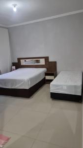 two beds in a room with white floors at Casa com piscina e lazer em SBC SP in São Bernardo do Campo