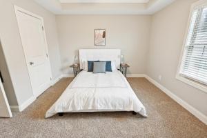 a white bedroom with a large white bed with blue pillows at Biltmore Luxury 1513 #2 Townhomes L 2bd 2 Bth in Clarksville
