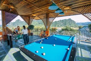 a pool table on the balcony of a resort with mountains at Green Riverside Cosy Home in Phong Nha