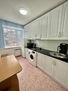 a kitchen with white cabinets and a washing machine at Уютная однокомнатная квартира в посёлке Щучинский in Uchitelʼ