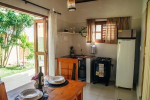 una cocina con nevera y una mesa con platos. en Dunas Pipa acomodações, en Pipa 26 fotos más