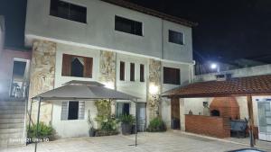 a white building with an umbrella in front of it at Casa com piscina e lazer em SBC SP in São Bernardo do Campo