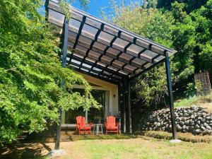 a pergola with two red chairs and a table at Wine Lodge Pucón in Pucón