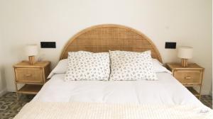 a bed with white sheets and pillows with two night stands at Escapada Rural en La Casa del Árbol in Tózar