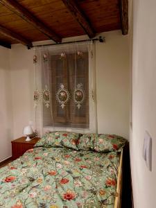 a bedroom with a bed with a floral bedspread and a window at Aristos Cottage in Káto Lekhónia +25 photos
