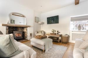 a living room with a fireplace and a chair at Wharton Cottage, Lake District Retreat in Cartmel