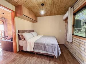 Un dormitorio pequeño con una cama y una ventana. en Morada Paraíso dos Canyons, en Praia Grande