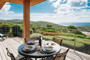 a table on a deck with a view of the ocean at Résidence Les Terrasses de Rondinara in Bonifacio