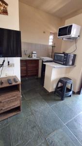 a kitchen with a microwave and a table and a stool at Apto Arejado em Ubatuba Próximo a Praia in Ubatuba