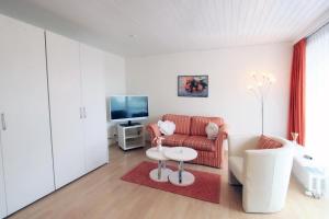 サンモリッツにあるApartment Skyline 110の赤いソファとテレビのあるリビングルーム