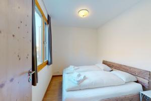 a bedroom with a bed with white sheets and a window at Apartment Blaunca in Maloja