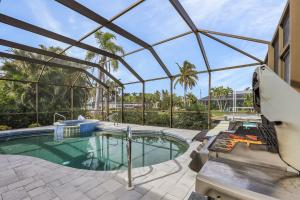 una piscina in una casa di vetro con patio di Waterfront Living, Dock, Heated Pool & Spa - Gulf Gate Oasis - Roelens a Cape Coral