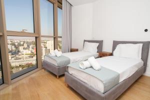 two beds in a room with a large window at WealthyStays 360 Luxury Residence in Nicosia